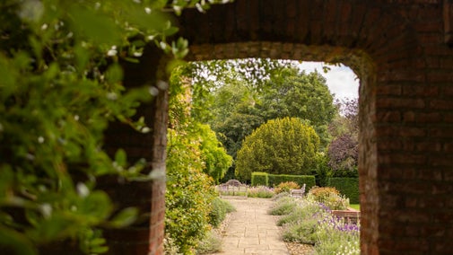 View of a floral garden through a bricked arch